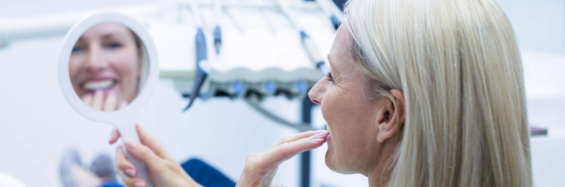 A woman looking at her dental bridges in the mirror