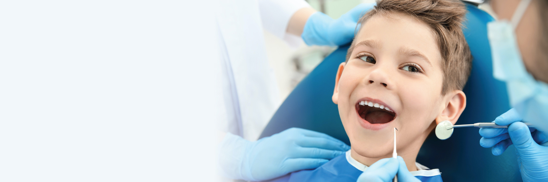 Smiling young boy in dental chair receiving a pediatric dental exam 