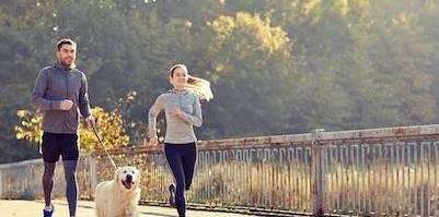 A couple jogging with their dog